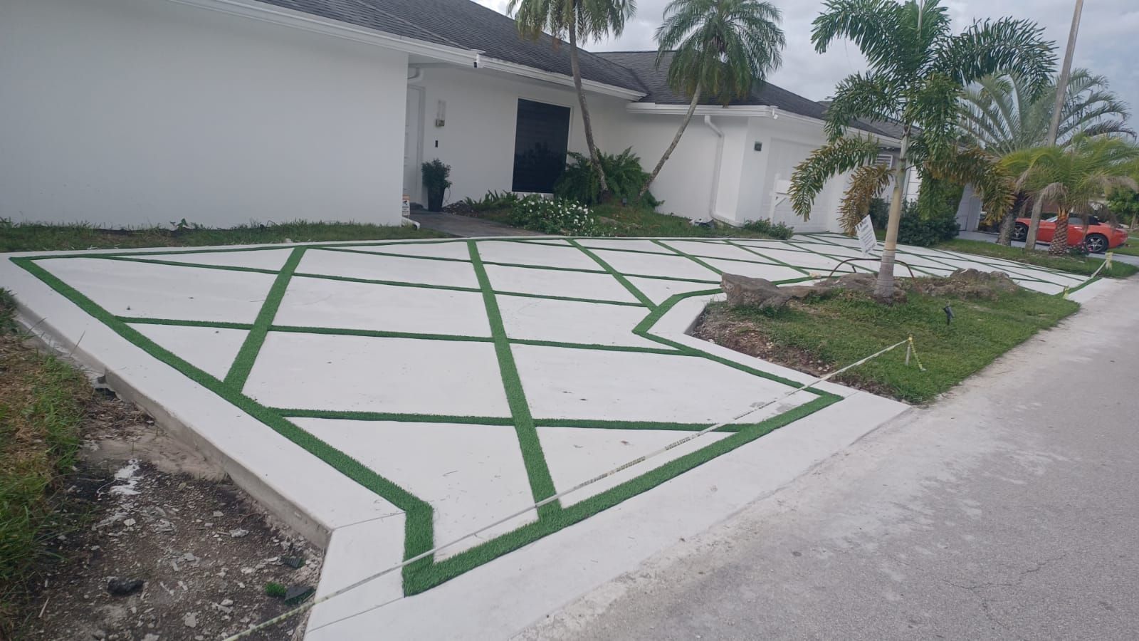 A white house with a green driveway in front of it.
