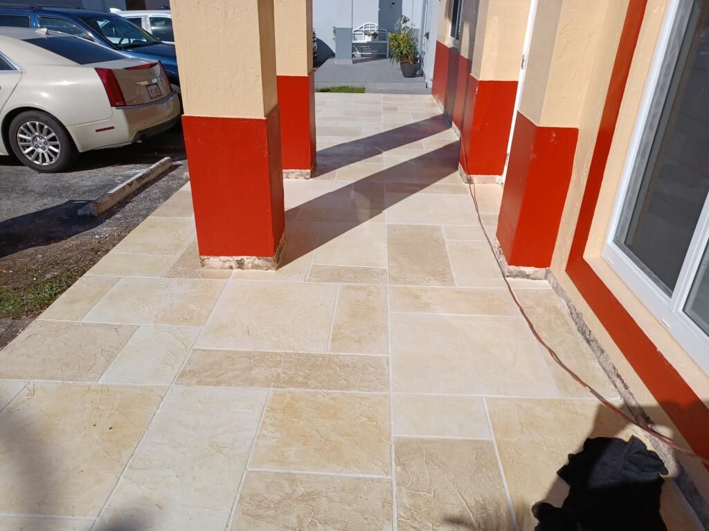 A white car is parked in front of a building with red pillars
