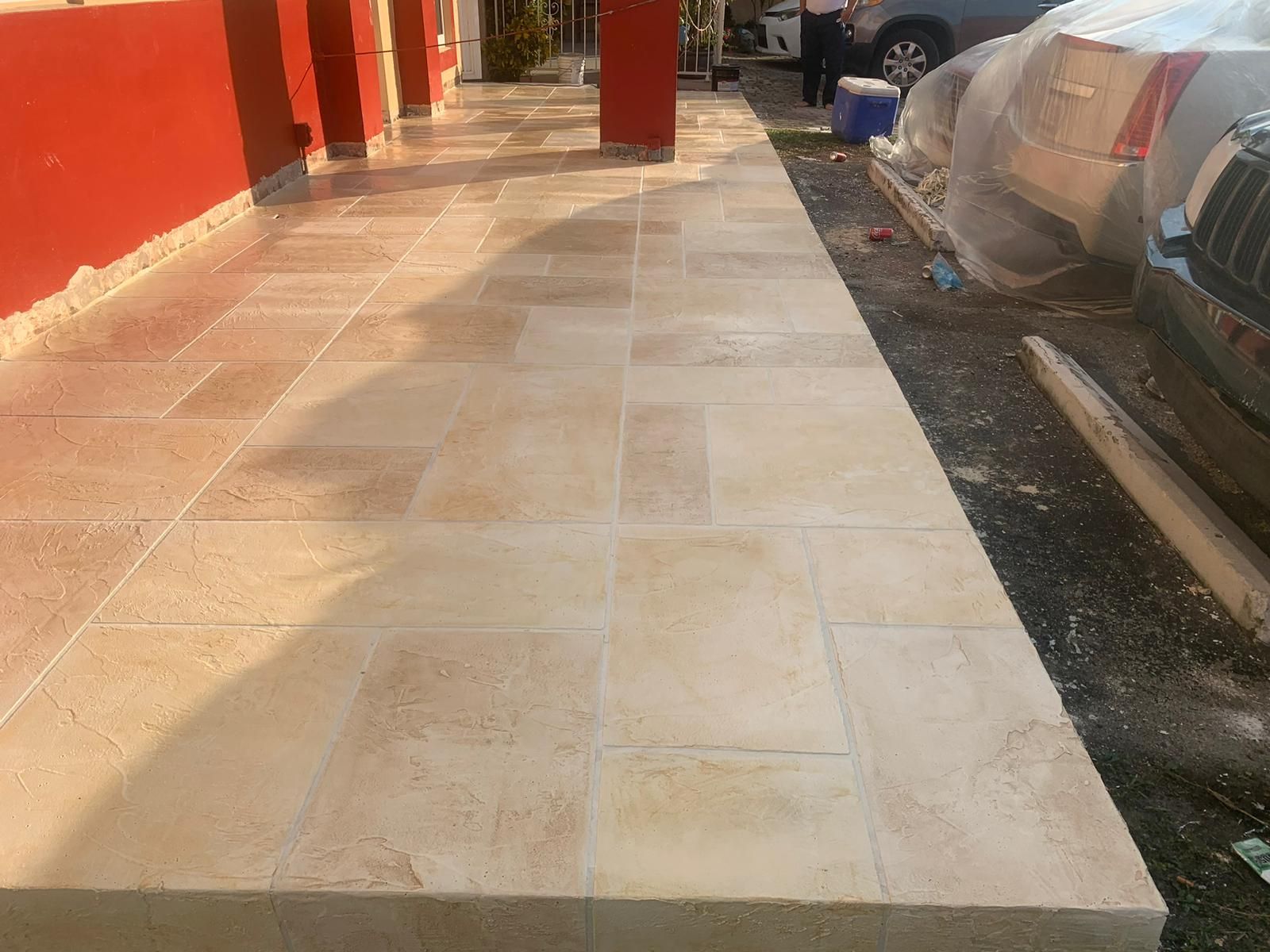 A tiled walkway with a car parked on the side of it.