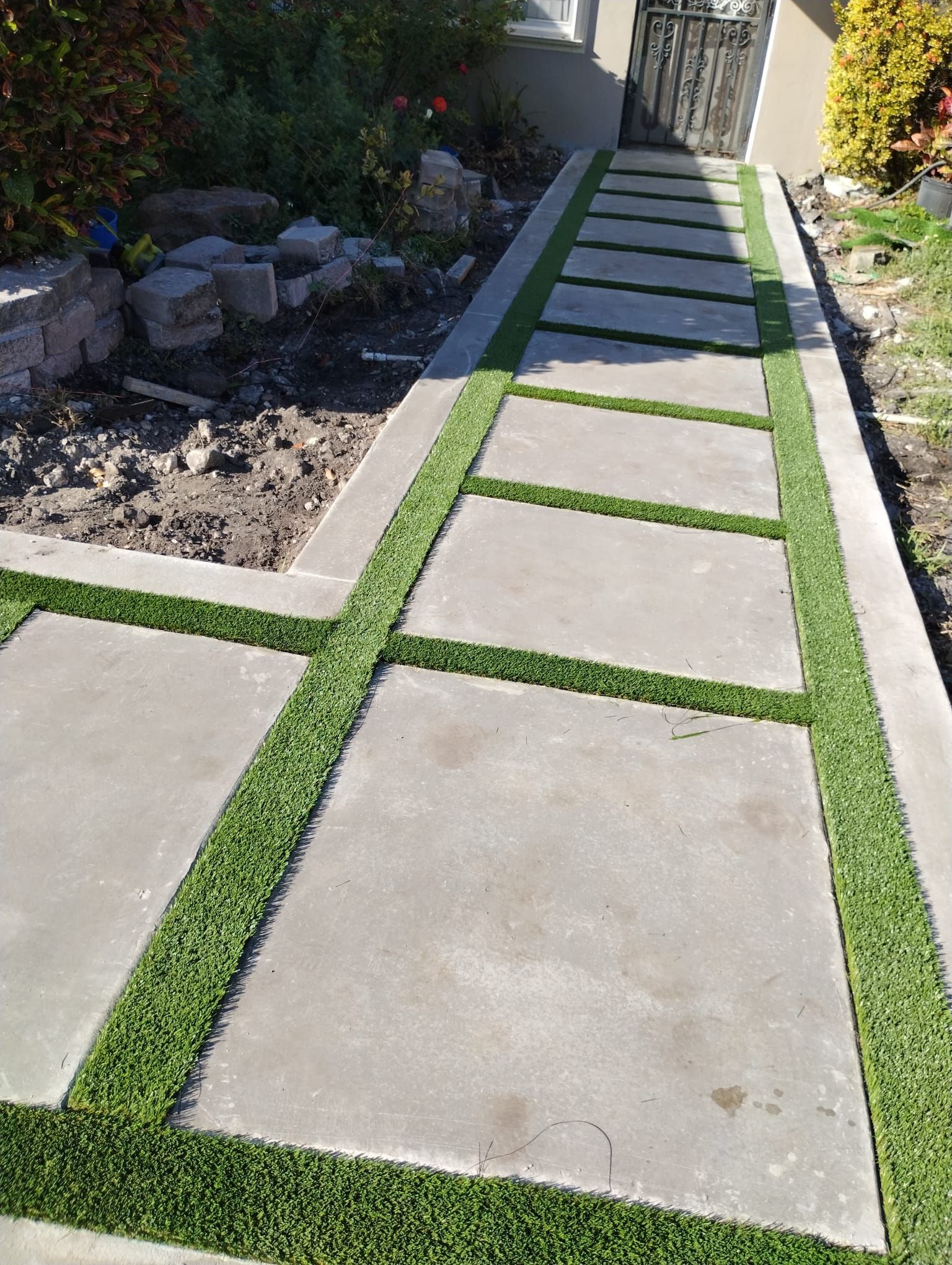 A concrete walkway with artificial grass on the side of it.