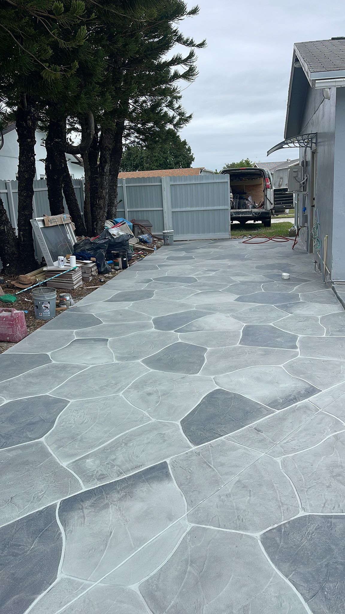 A Stone Walkway Leading to A House with Trees in The Background.