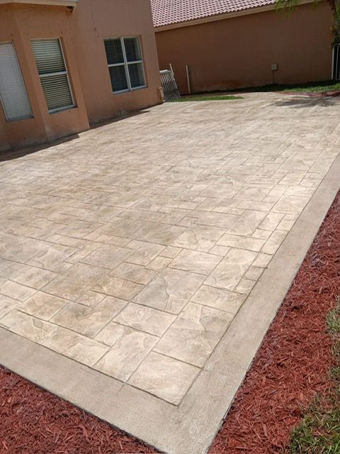 A patio with a border of red mulch in front of a house.