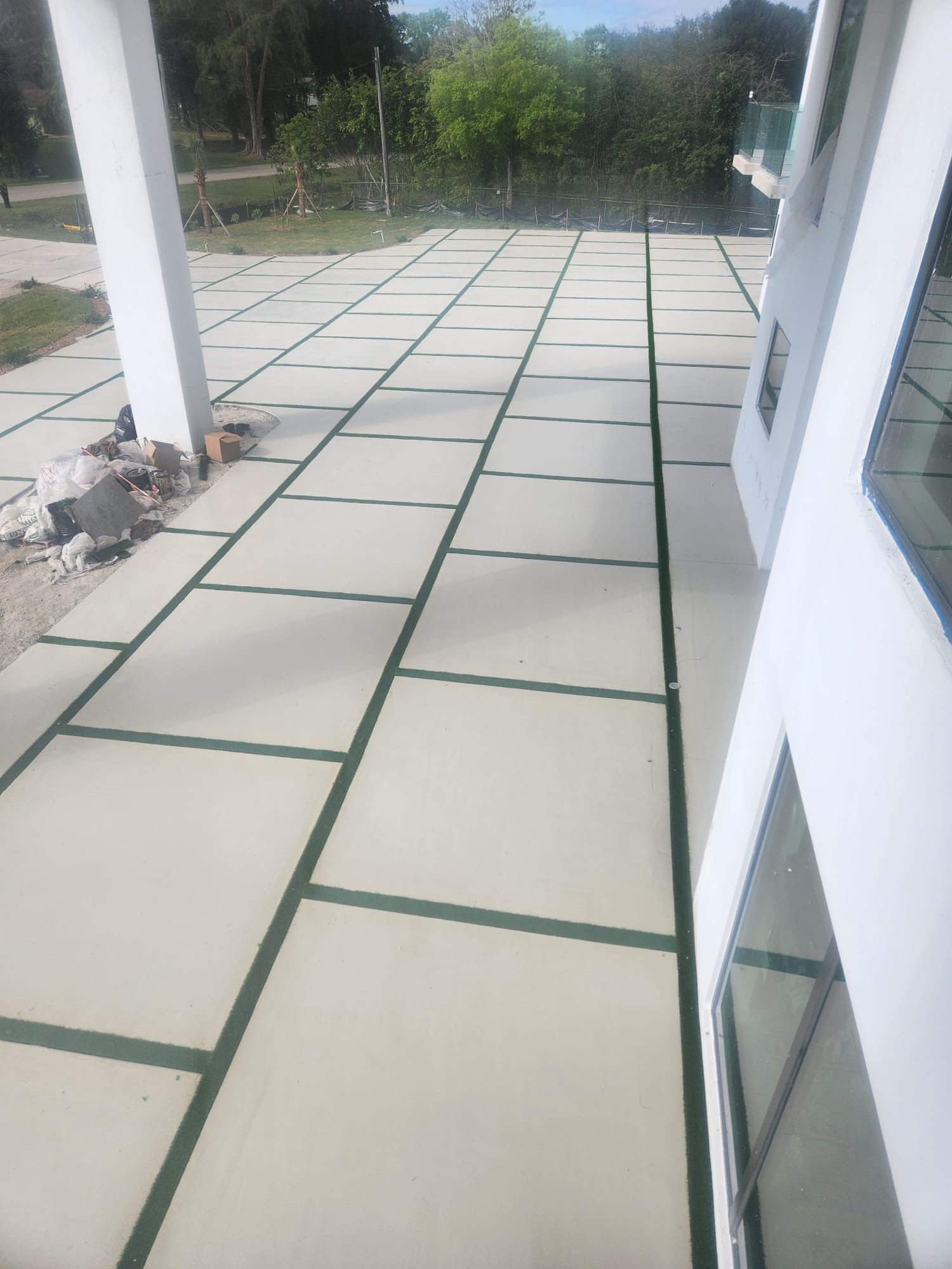 A concrete walkway with green stripes is being built in front of a house.