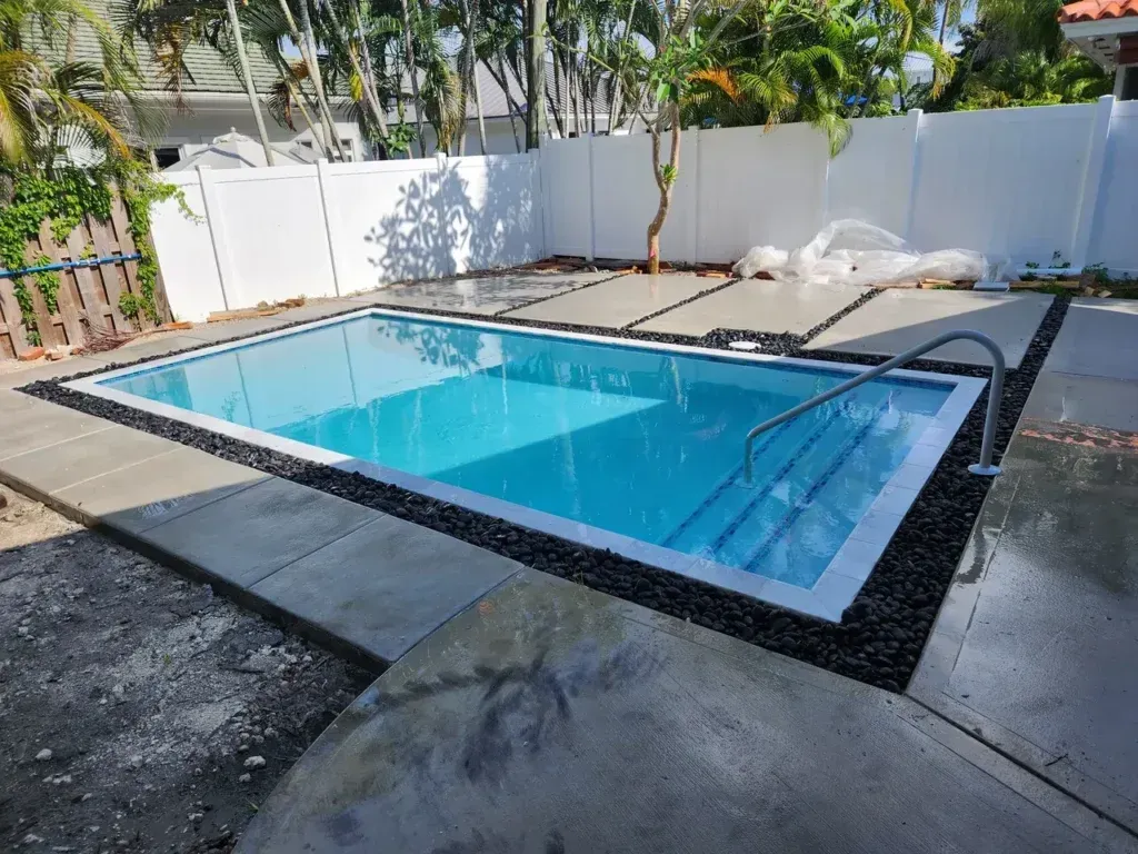 A large swimming pool is sitting in the backyard of a house.