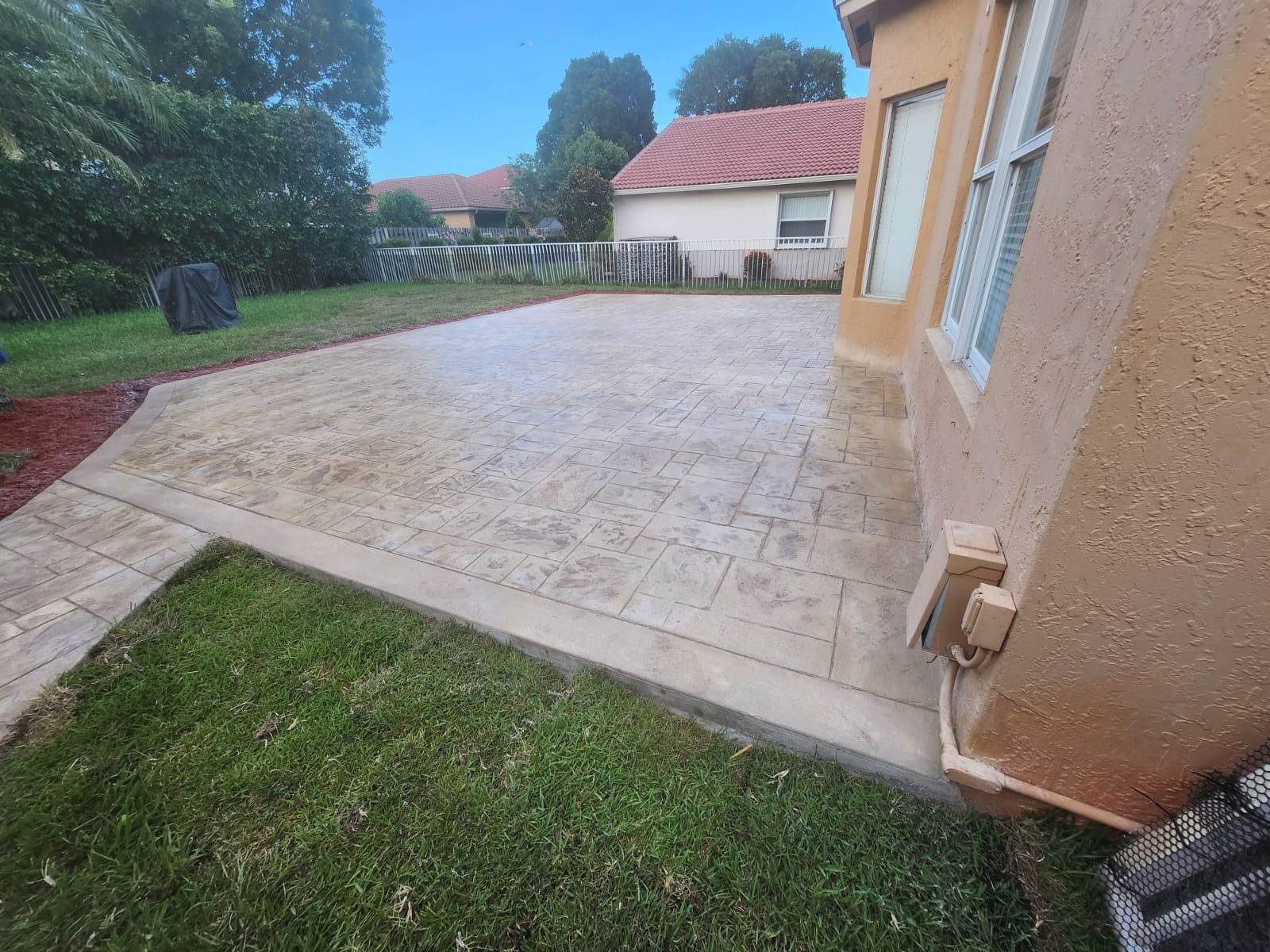 A concrete walkway leading to a house in a backyard.