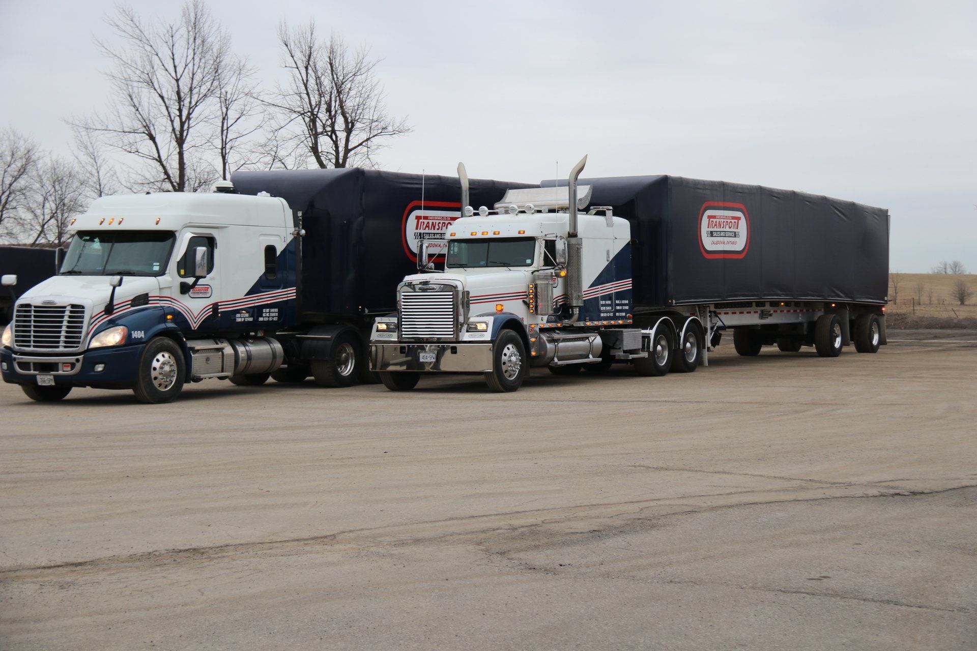Three semi trucks are parked next to each other in a parking lot.