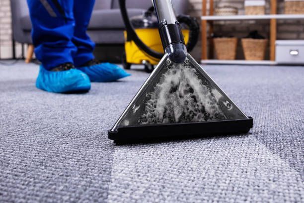 A janitor performing professional carpet cleaning with a vacuum cleaner.