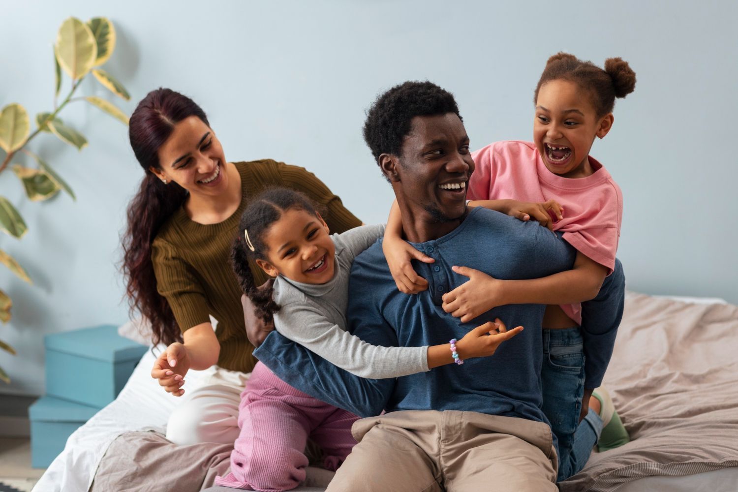 A family is sitting on a bed playing with each other.