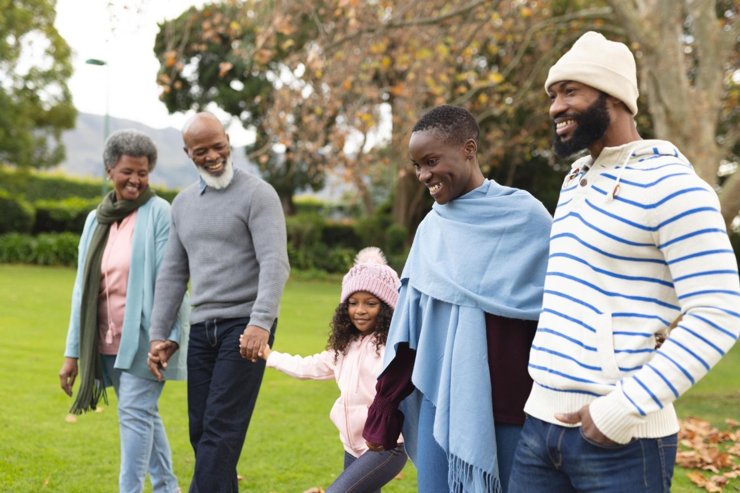 A family is walking in a park holding hands.