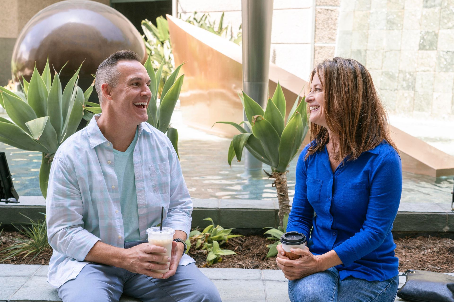 A man and a woman are sitting on a bench talking to each other.