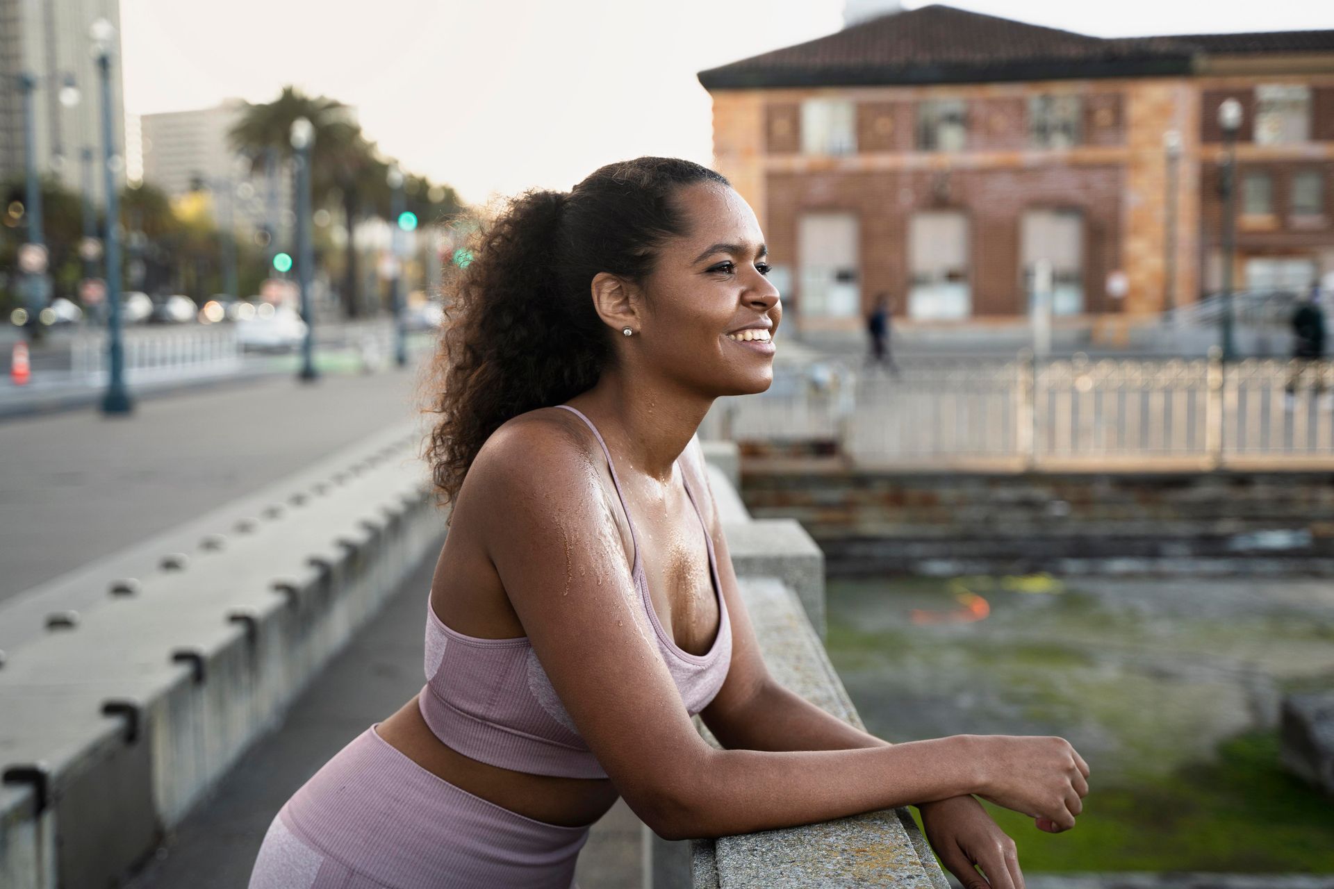 A woman is leaning on a railing and smiling.