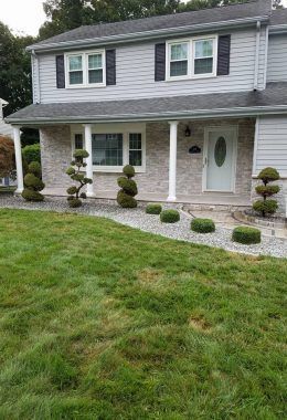 Two-story house with gray siding, white columns, and manicured landscaping.