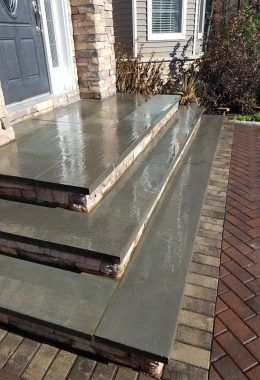 Gray stone steps with brick edging leading to a dark door.