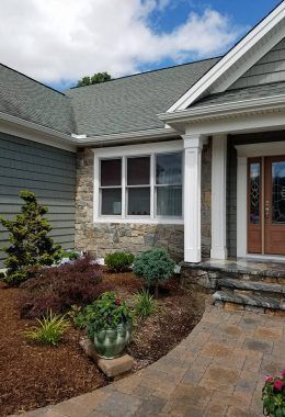 House exterior with stone facade, landscaped garden, and a walkway leading to the front door.