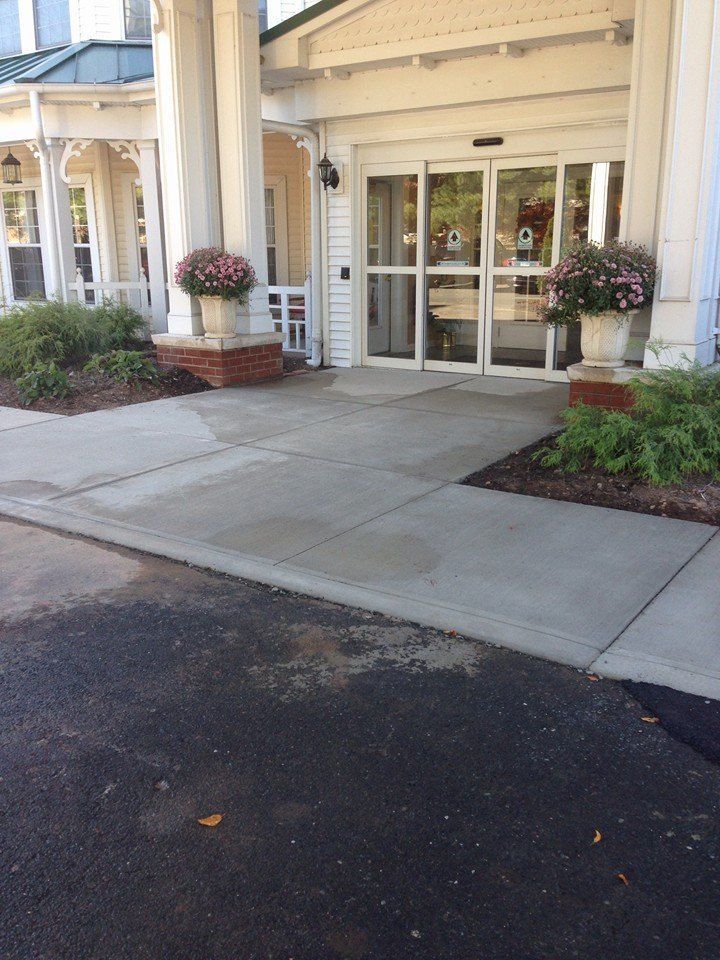 Exterior view of building entrance with automatic sliding doors, planters, and concrete walkway.