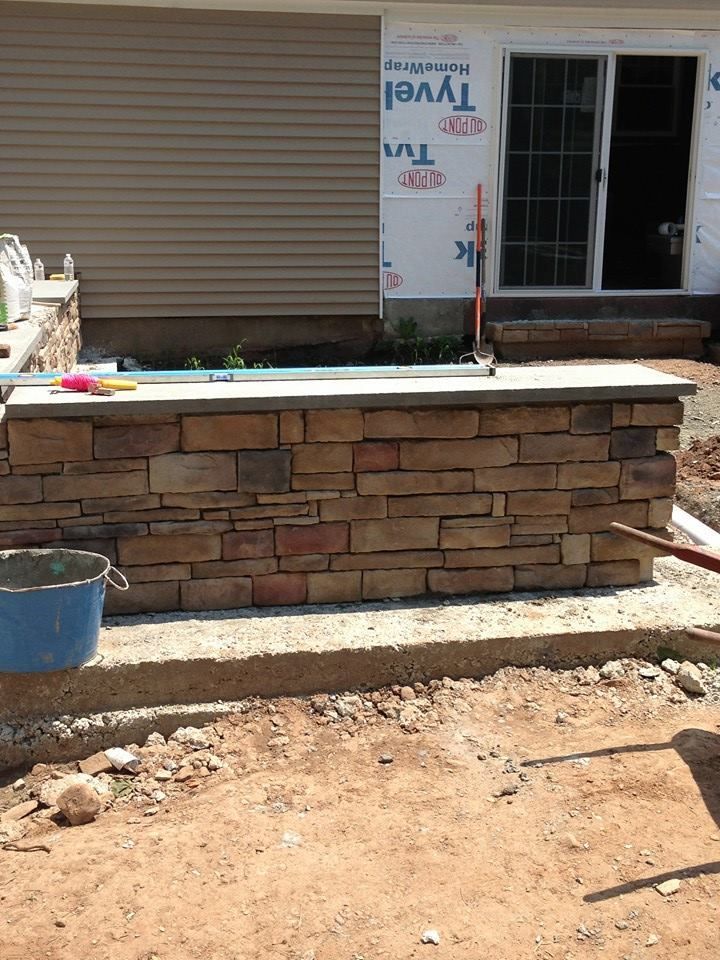 Stone brick outdoor bar under construction near a sliding glass door.
