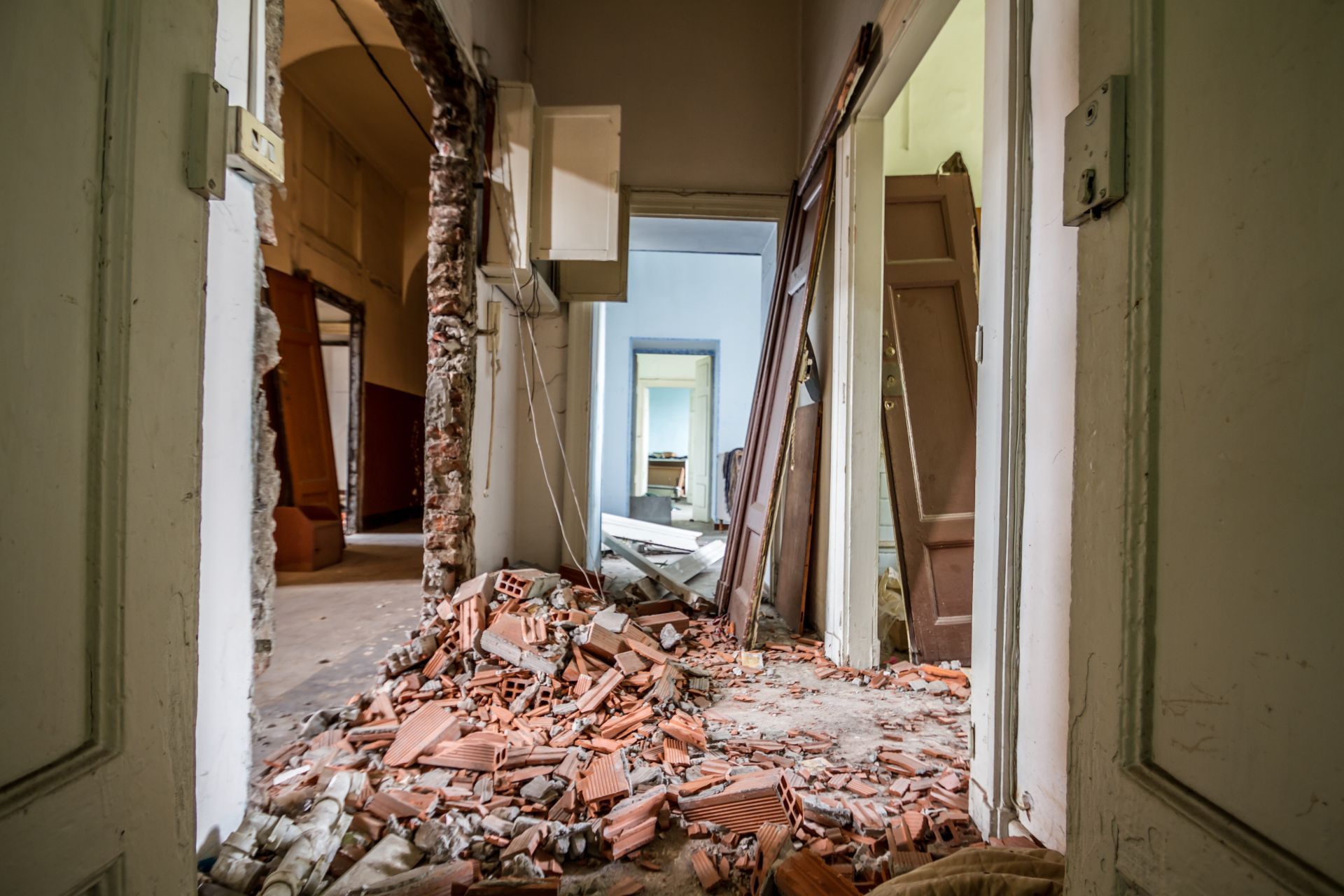 Interior hallway with rubble, damaged walls, and open doorways.