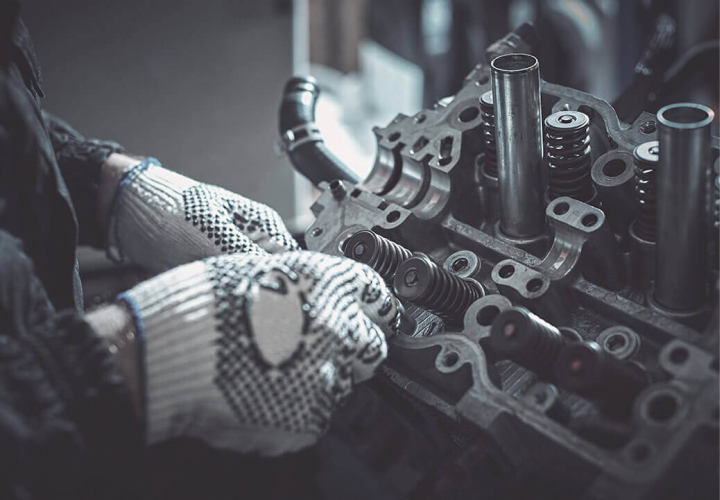 A man wearing gloves is working on a car engine | 1 Auto Center Corp