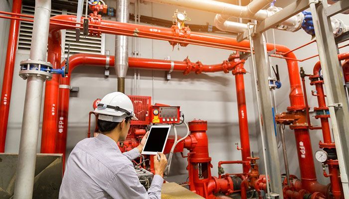 Red fire alarm control panel with a display, buttons, and various internal components.