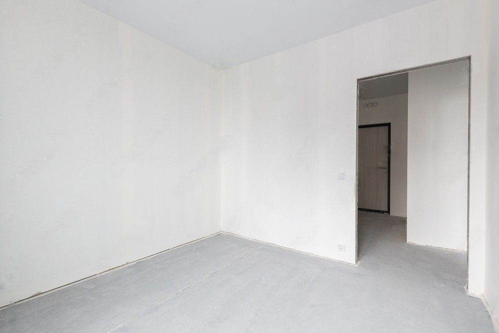 Empty concrete space with partitions, unfinished interior.