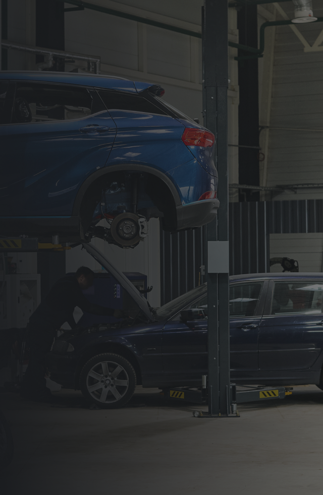 Cars in a repair shop; one raised on a lift, another under repair, blue vehicles. |  Bama Direct Automotive Llc
