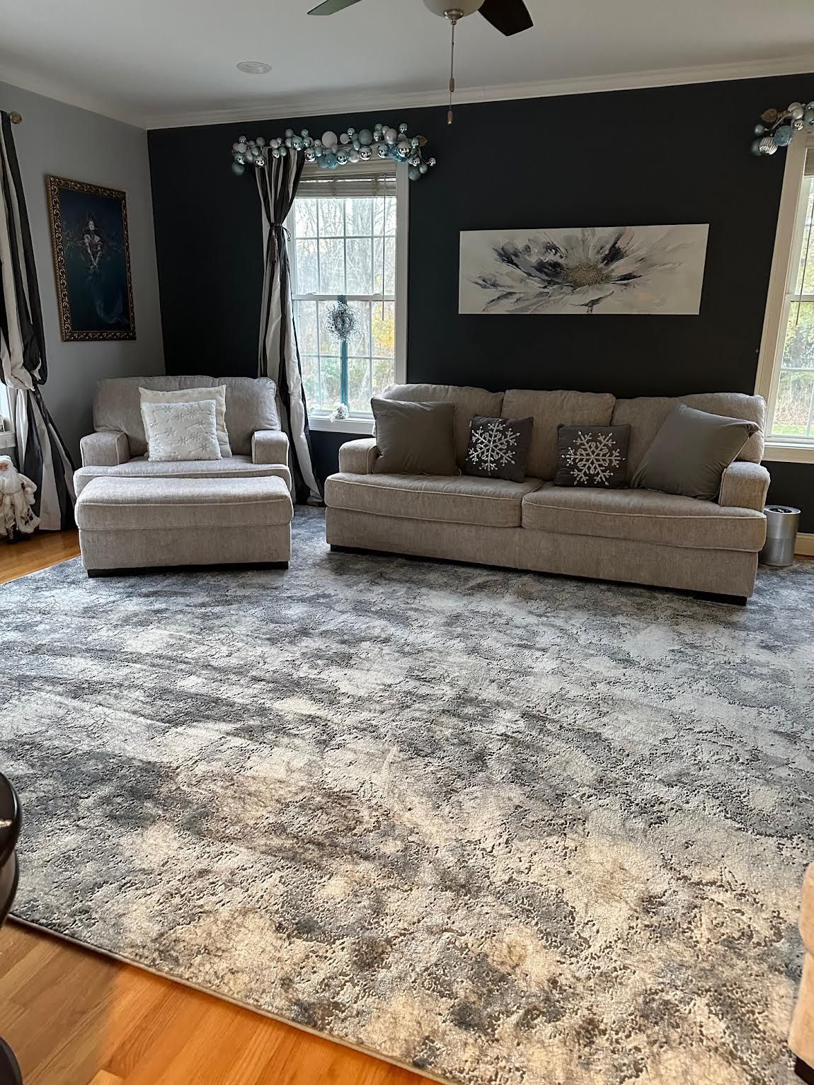Living room with dark walls, beige sofa and chair, large gray shag rug, and framed wall art.