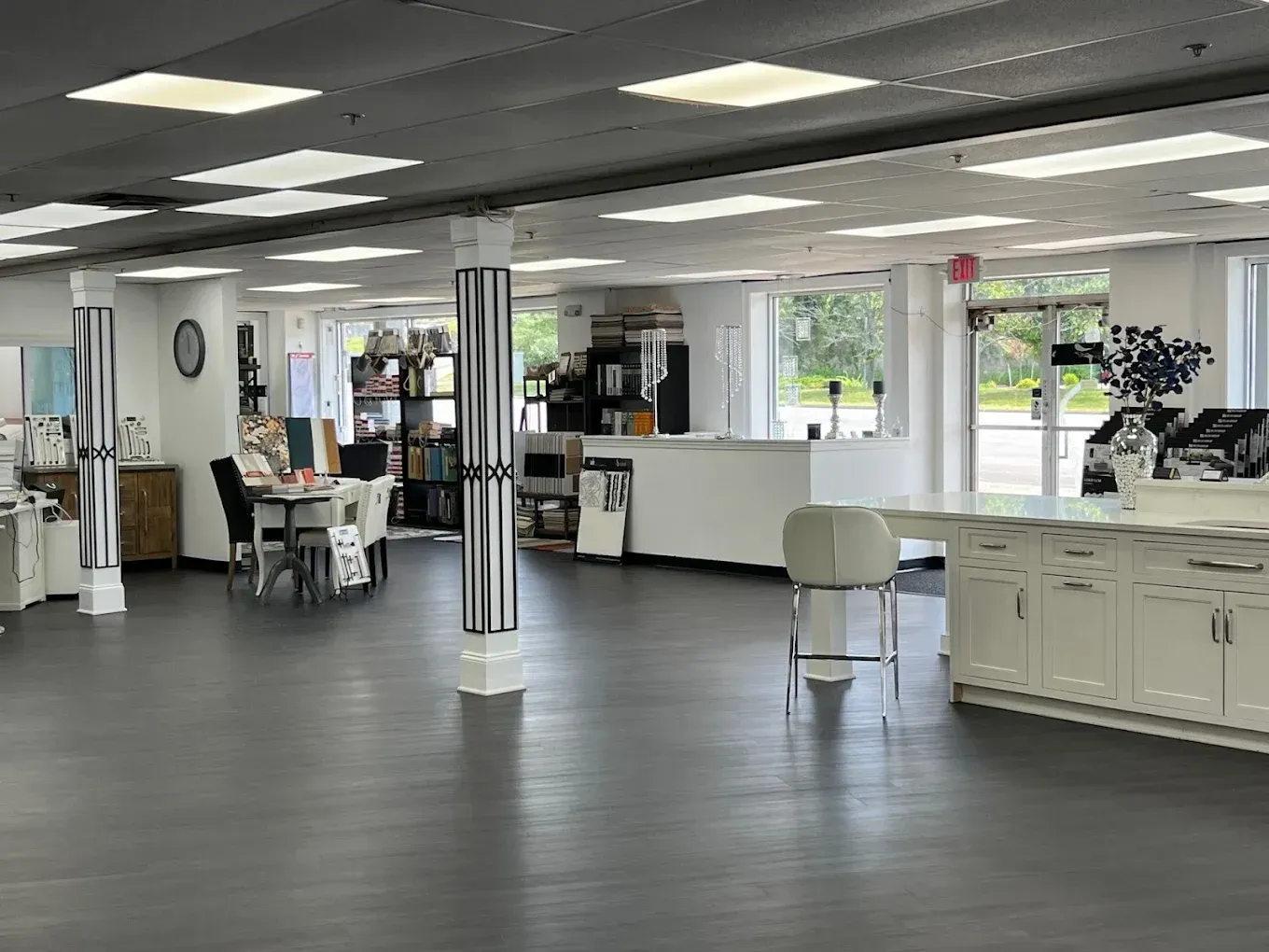 Spacious, bright retail interior with gray floor, white walls, and display areas. Two striped columns.