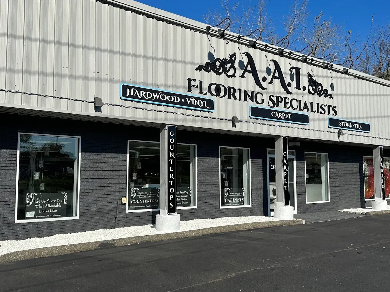 Exterior of A.A.I. Flooring Specialists store with gray and black exterior and windows; sign says
