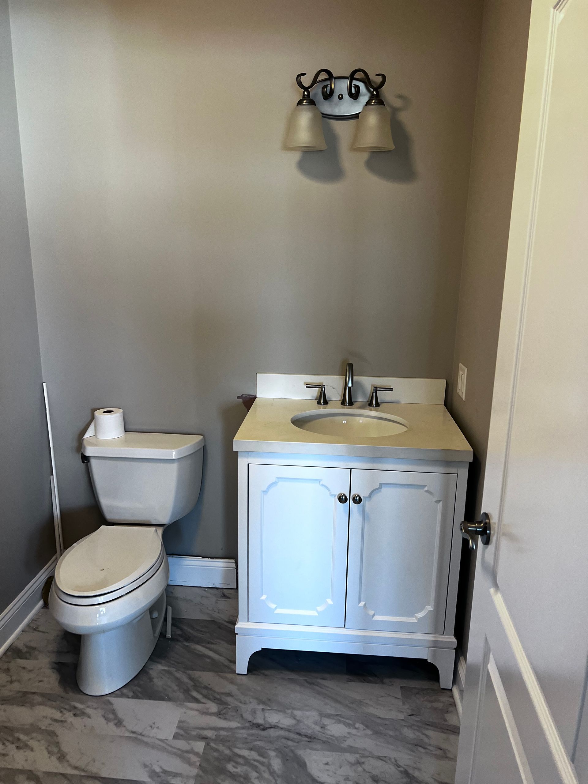 Small bathroom with toilet, white vanity sink, and wall light fixture.