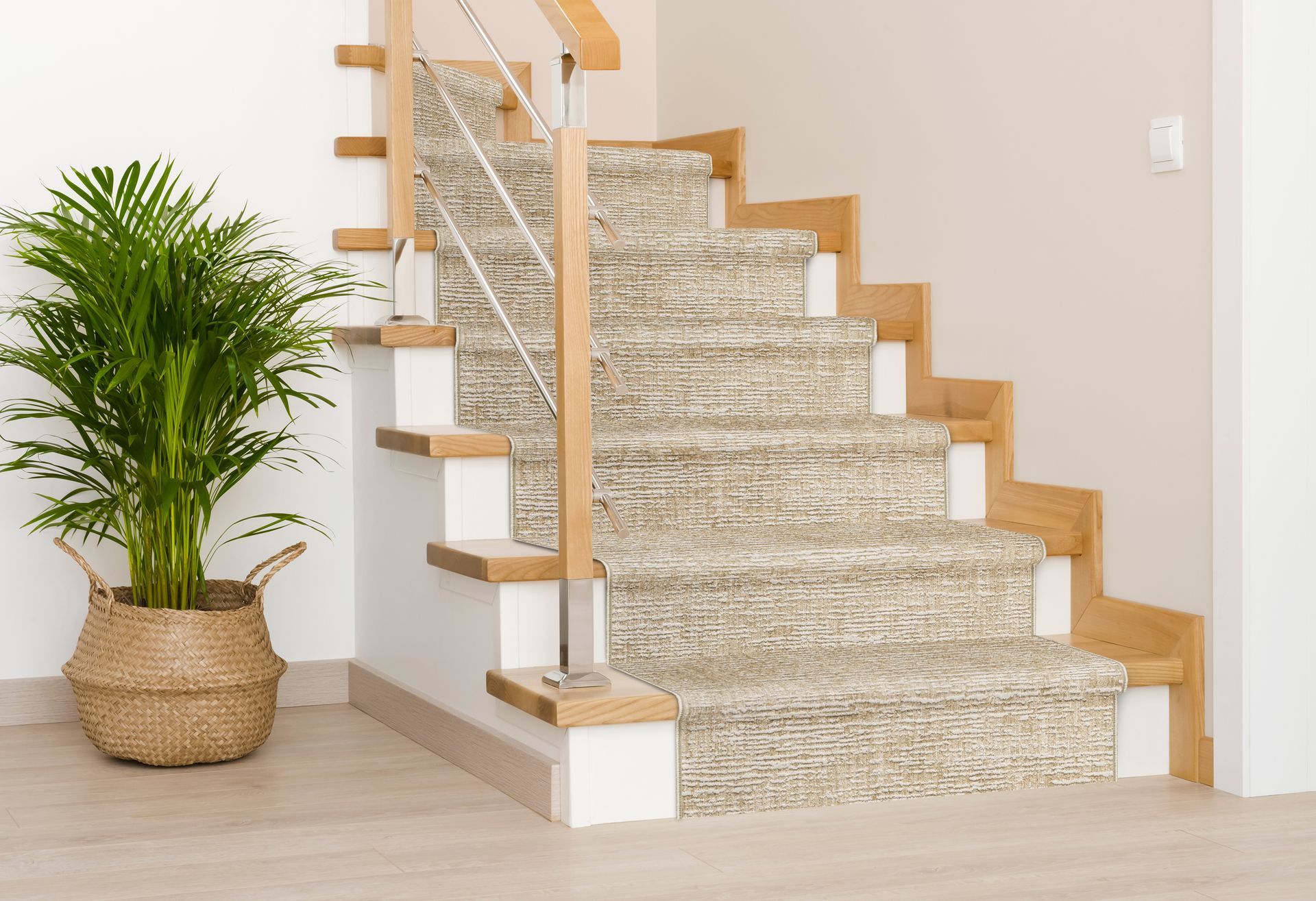 Staircase with wooden steps and carpet, next to a potted plant in a woven basket.