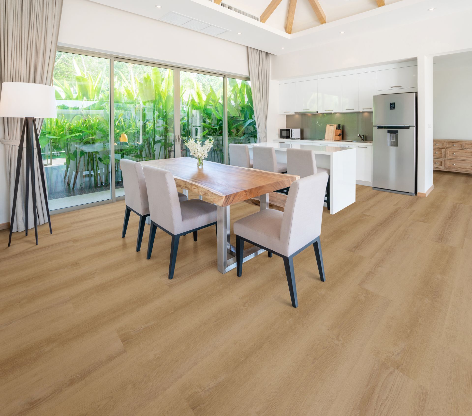 Bright open dining and kitchen area with white furniture, wood floors, and large sliding glass doors to a patio