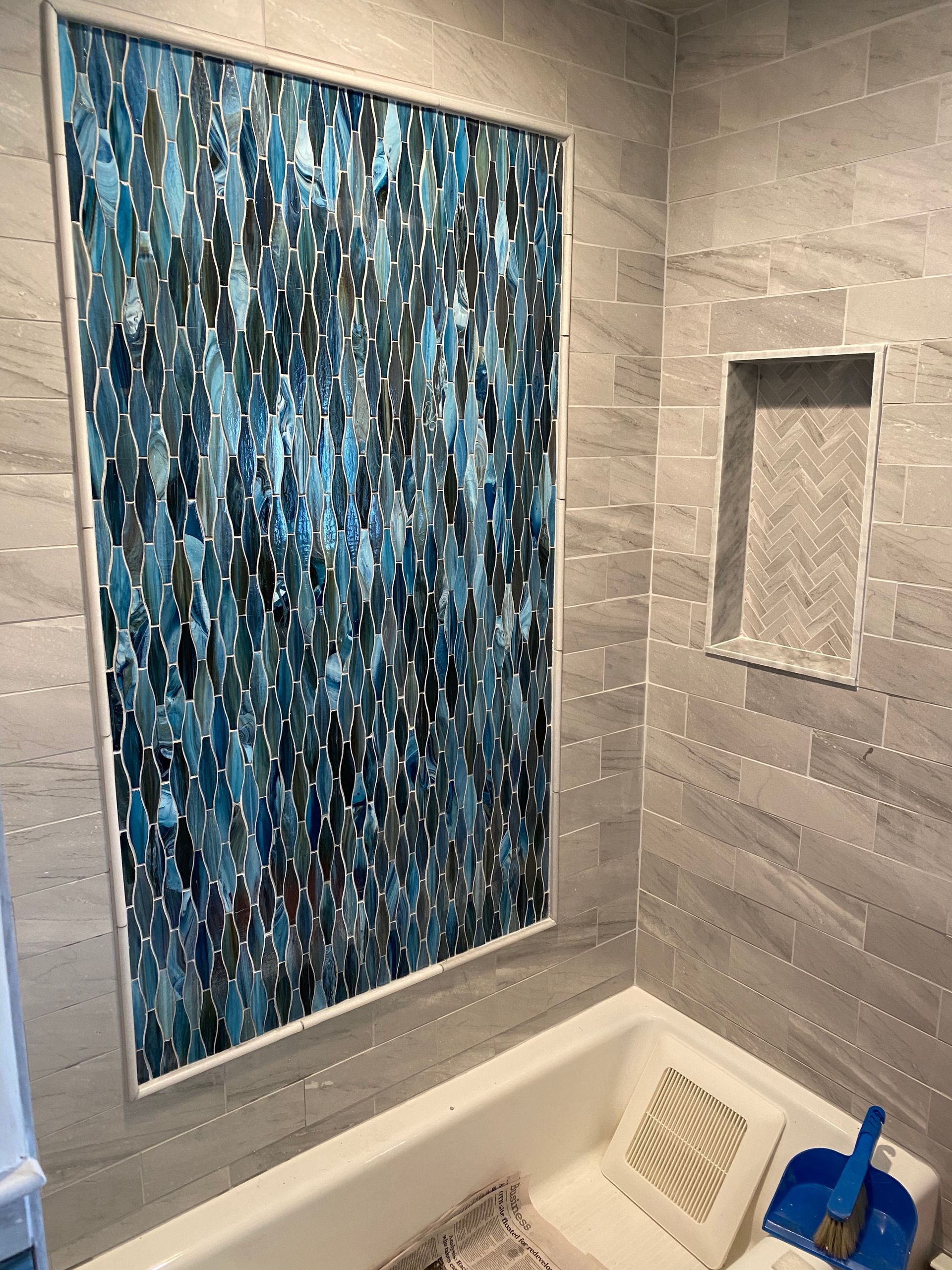 Bathroom with blue abstract wall art above the tub and a recessed shower niche.