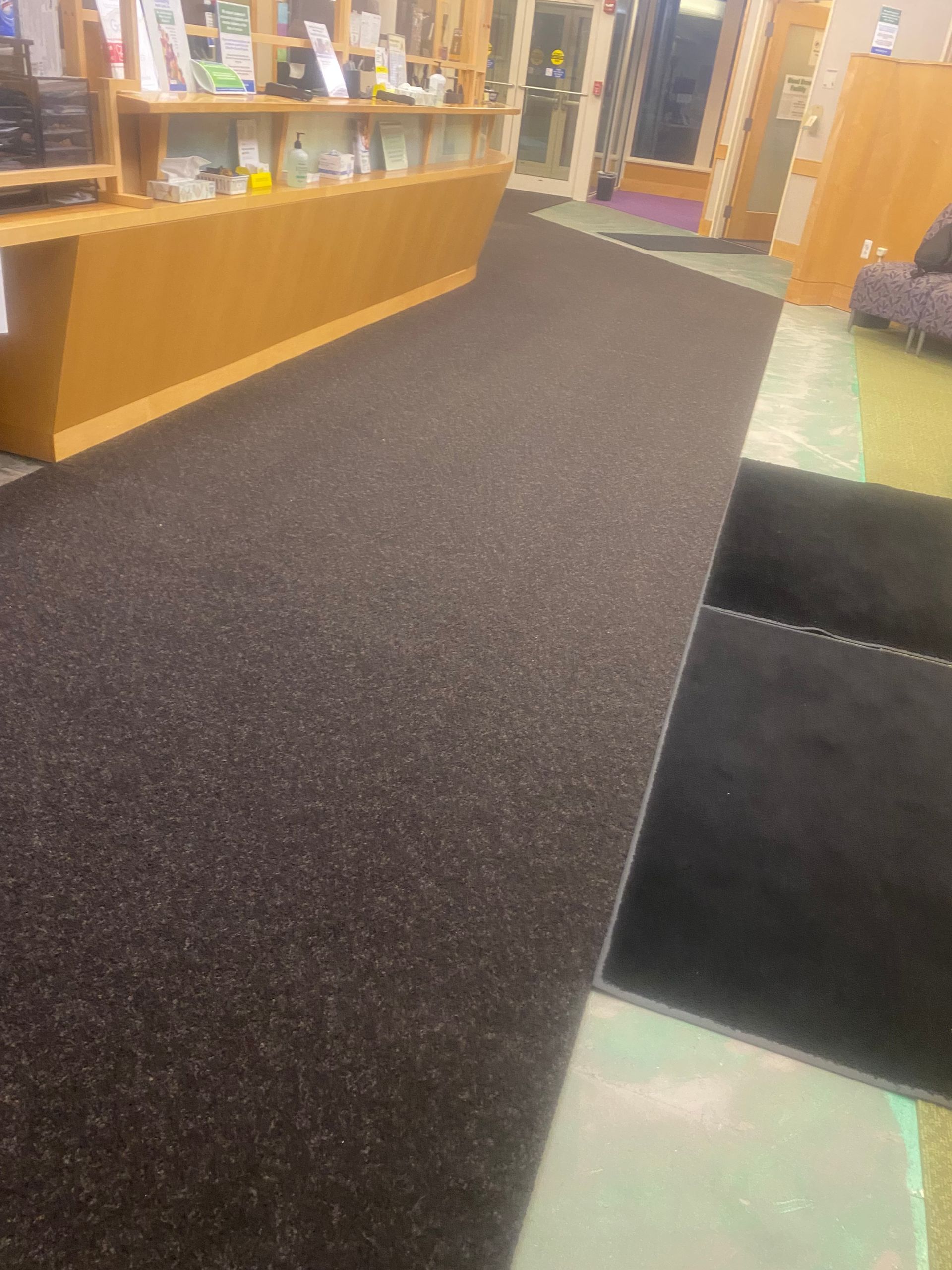 Library aisle with a dark carpeted floor, wooden shelves, and a display counter along the left side.