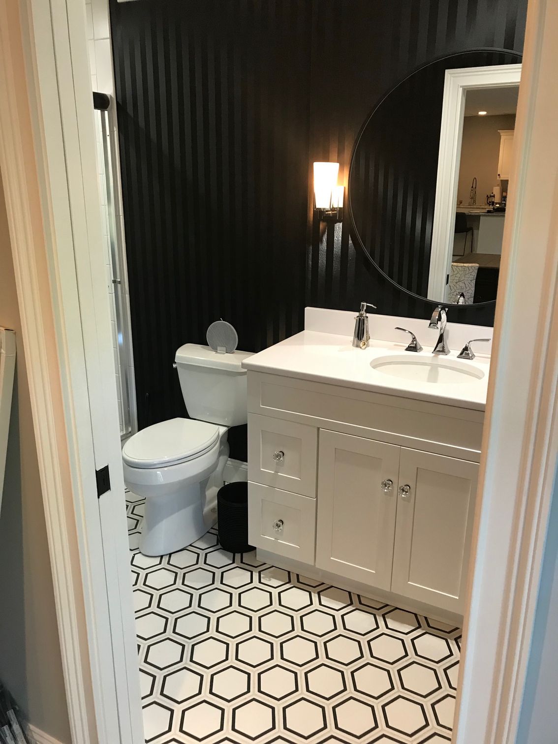 Modern bathroom with black walls, white vanity, toilet, and patterned hexagon tile floor