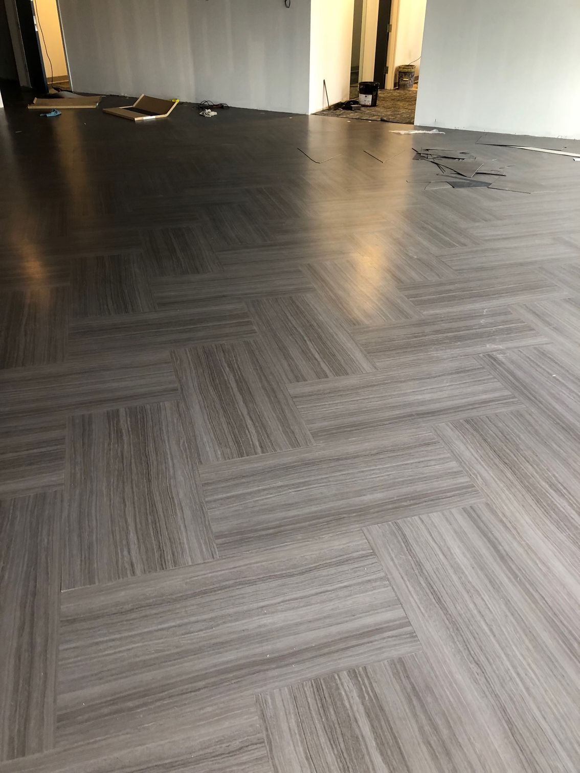 Gray patterned carpet tiles in a mostly empty room with white walls and a doorway in the back.