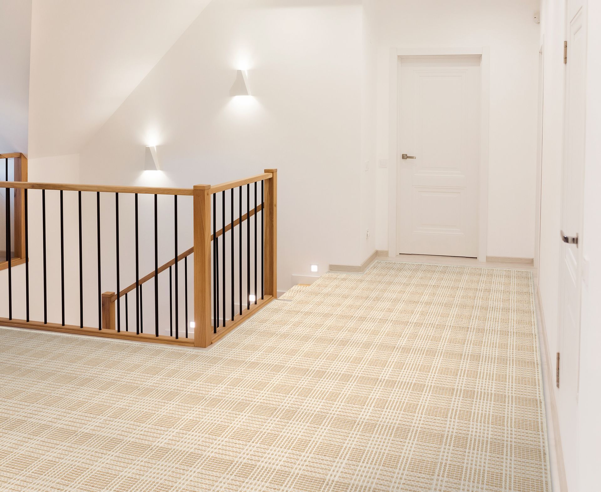 Hallway with cream-colored patterned carpet, wooden railing, and white walls. A staircase and door are visible.