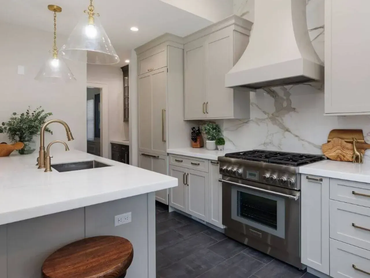 Modern kitchen with light gray cabinets, white countertops, stainless steel appliances, and gold hardware.