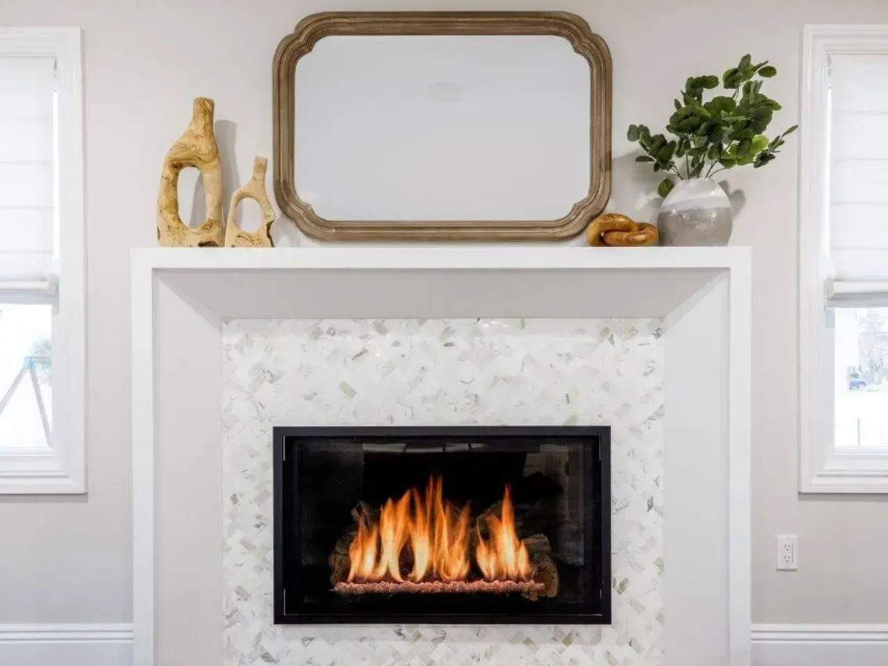 Fireplace with white mantle, marble tile surround, mirror, and decorative items.