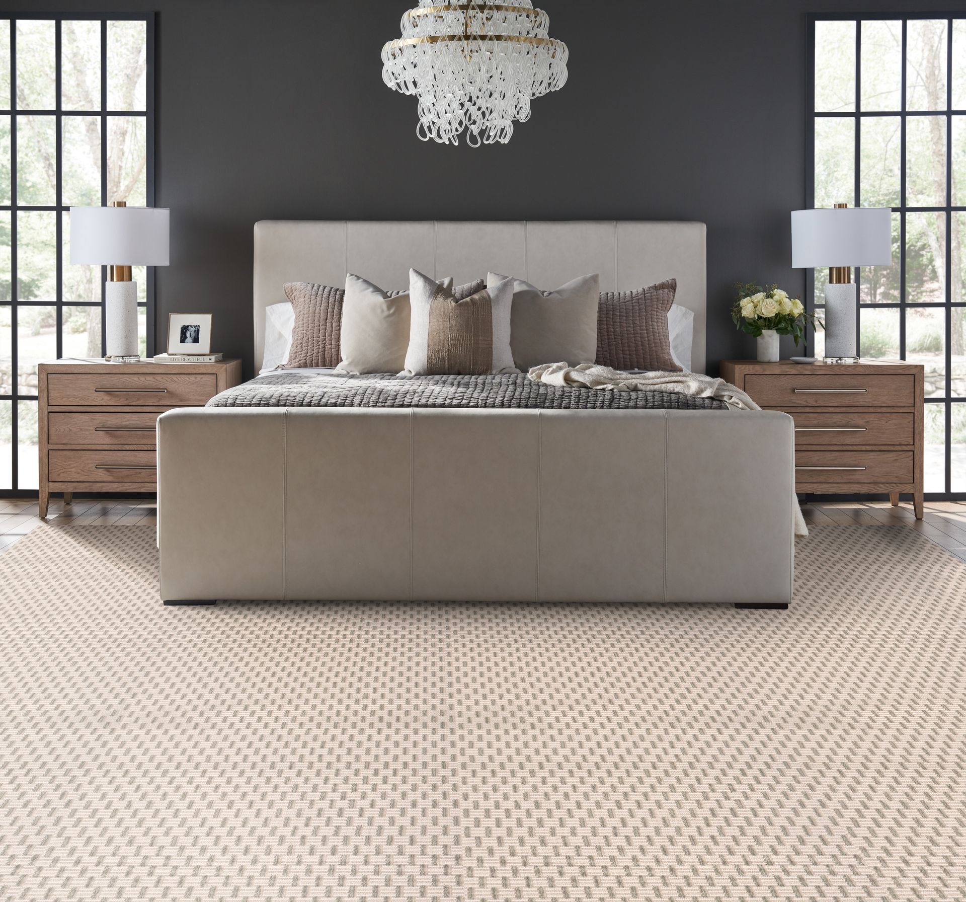 Bedroom with a bed, nightstands, lamps, rug, and windows. Neutral colors.