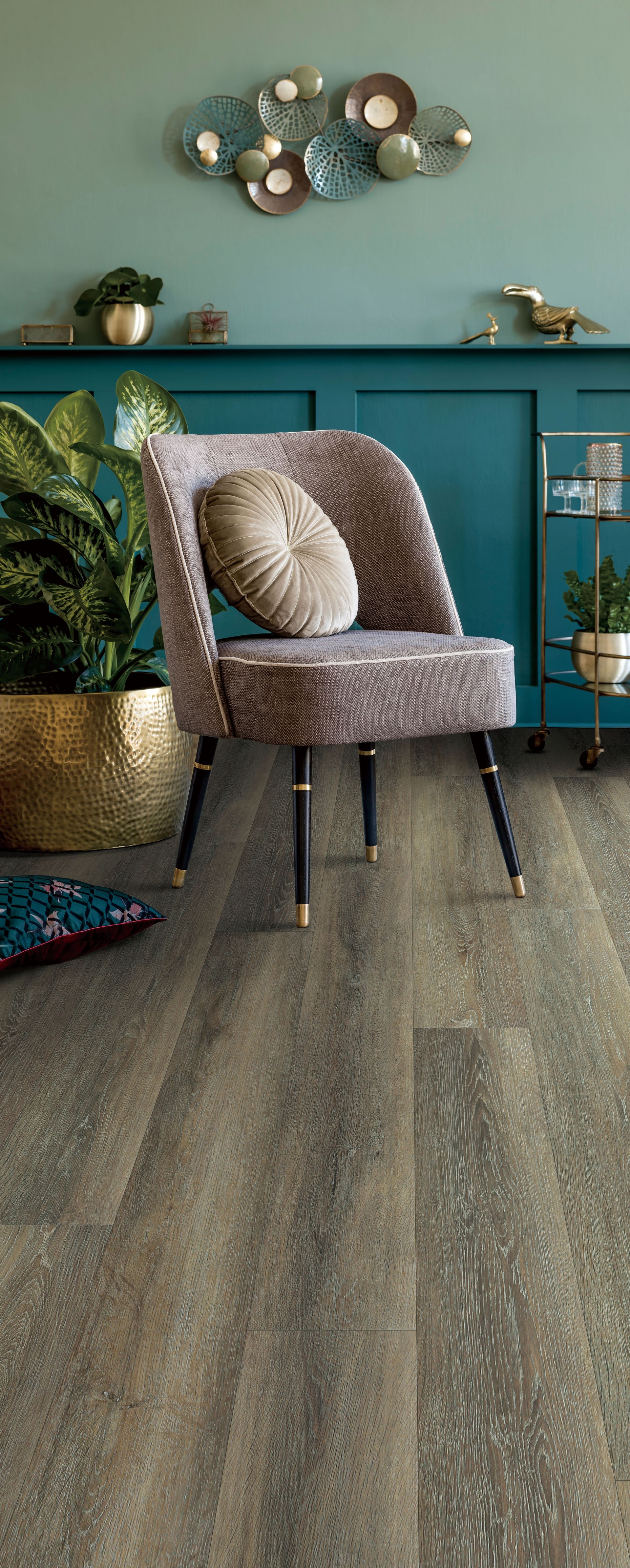 Gray upholstered chair on a dark floor in a teal room with a decorative wall shelf