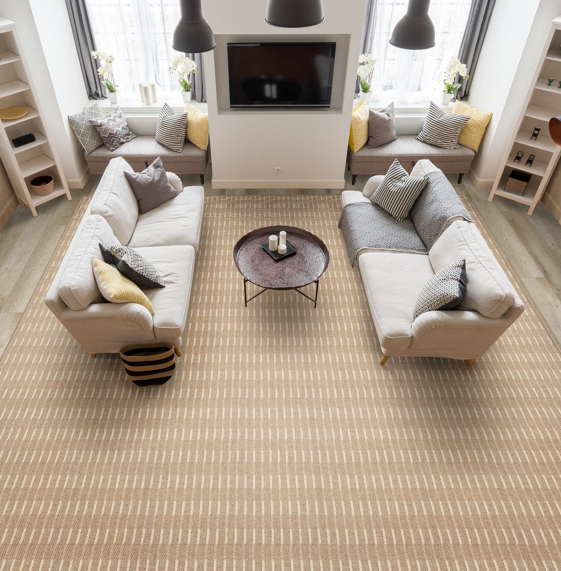 Living room with two cream sofas, a round coffee table, and a large rug, centered under a mounted TV.