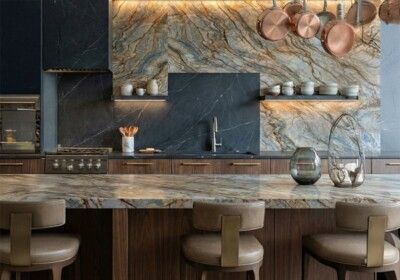 Modern kitchen with marble countertops, wood cabinets, copper pots, and bar stools.