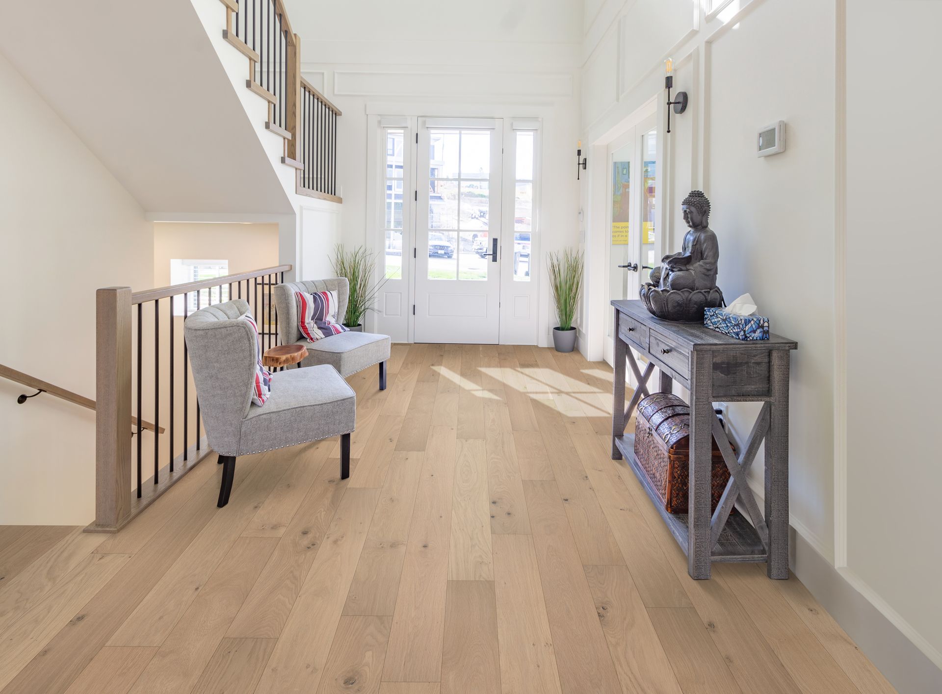 Light wood-floored entryway with chairs, console table, stairs, and bright front door.