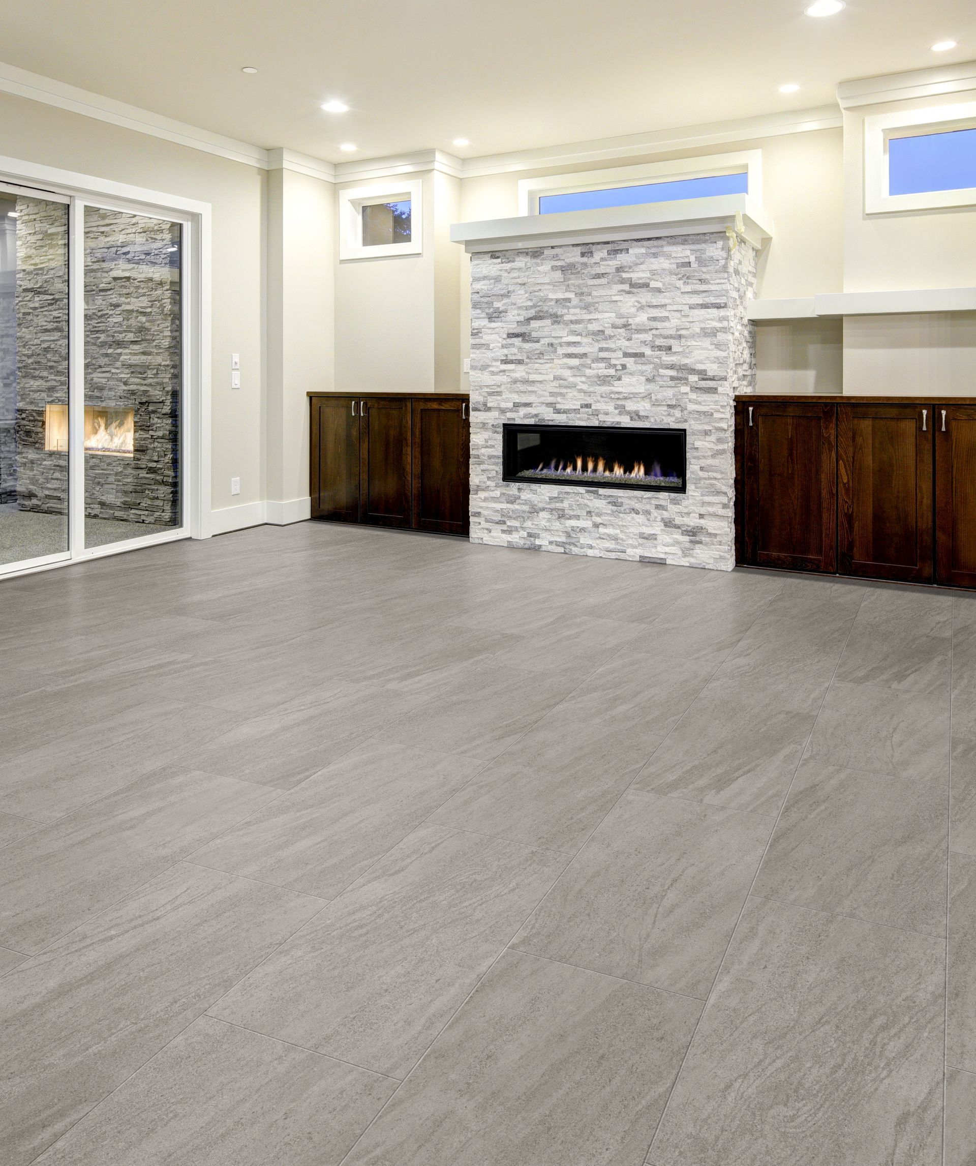 Empty modern living room with gray carpet, stone fireplace, and sliding glass doors
