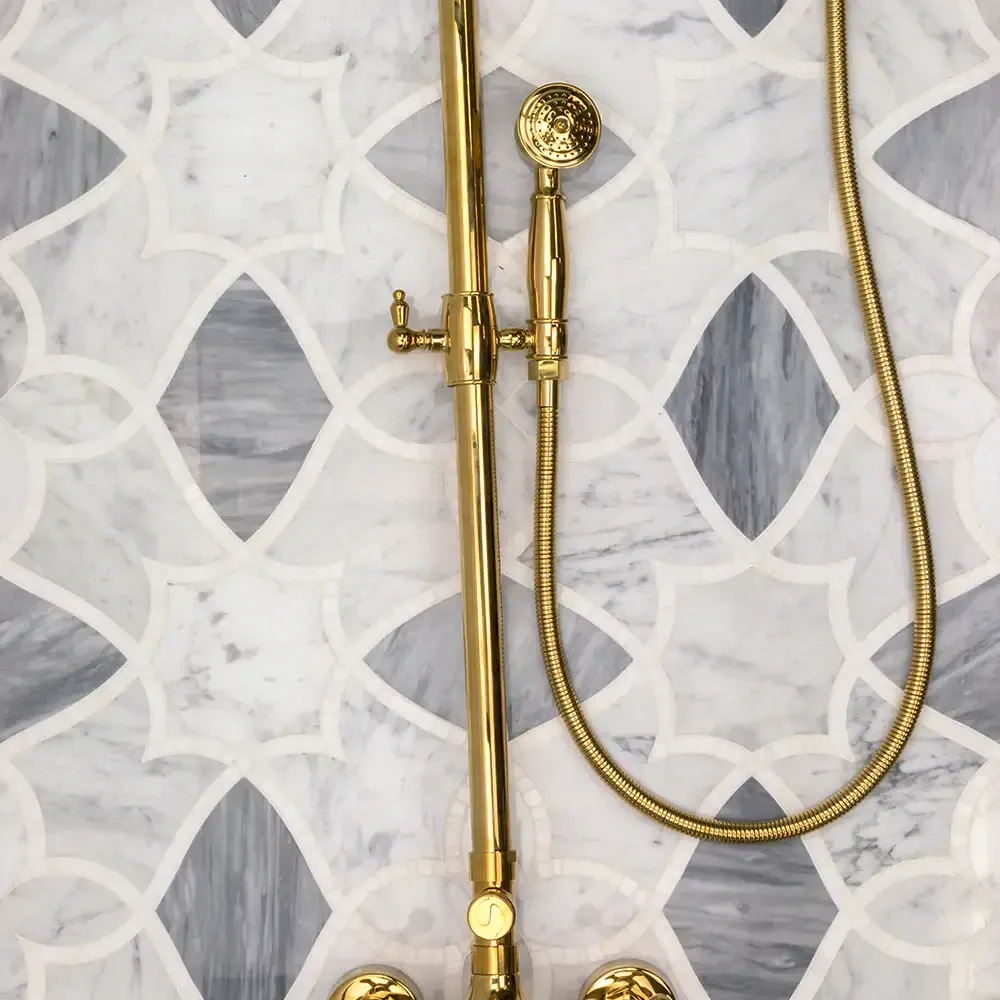 Gold shower fixtures against patterned gray and white tile.