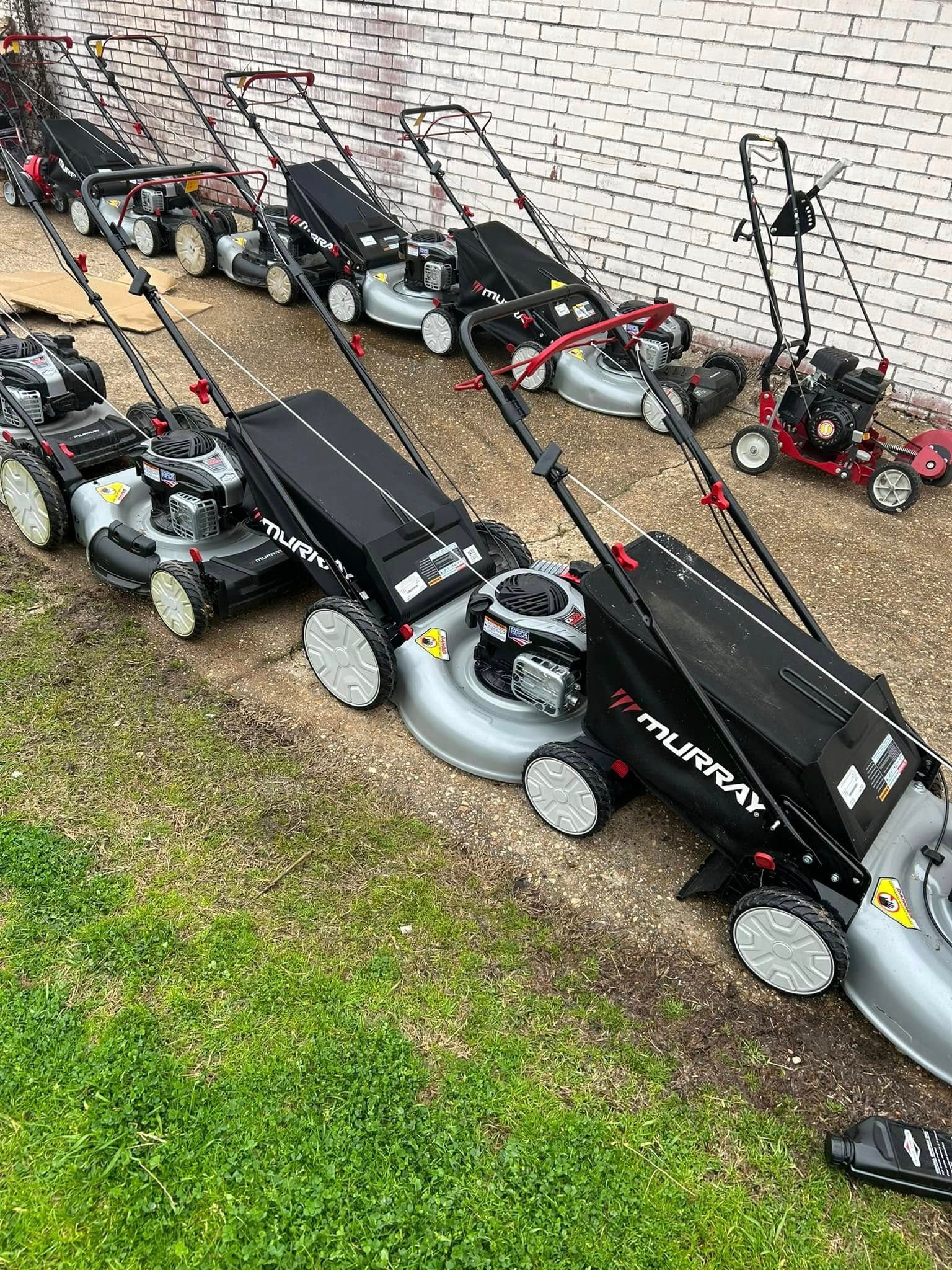 A row of lawn mowers sitting on top of a lush green lawn.