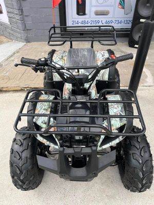 A camouflage atv is parked on the sidewalk in front of a building.