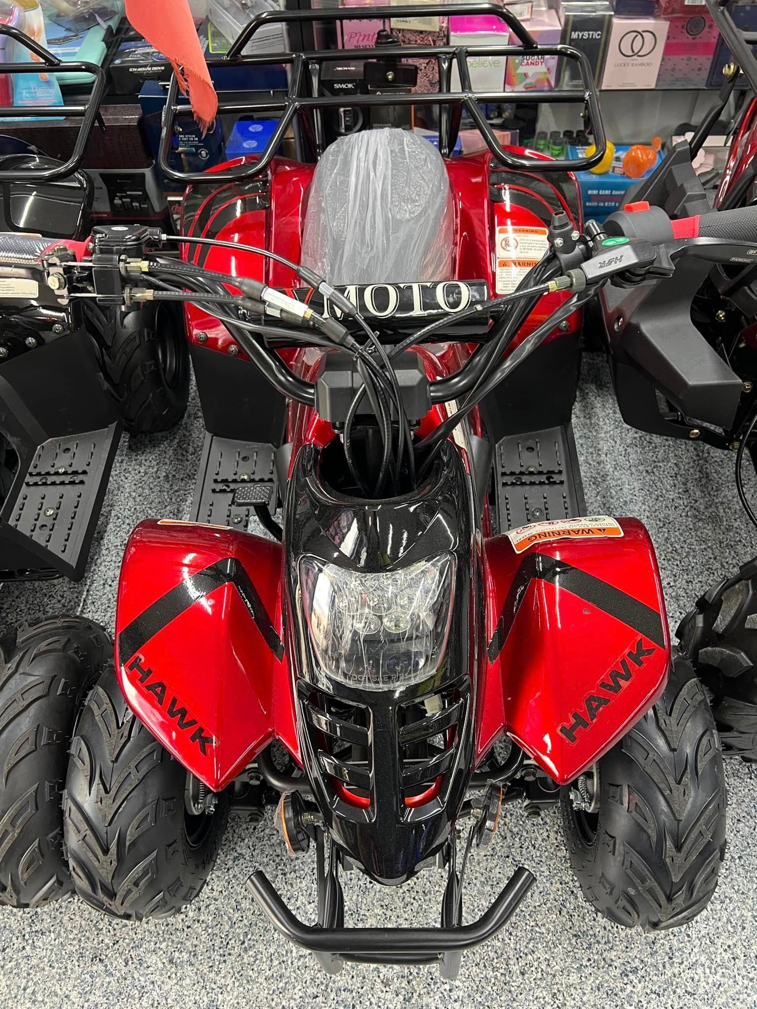 A red atv is sitting on top of a concrete floor.