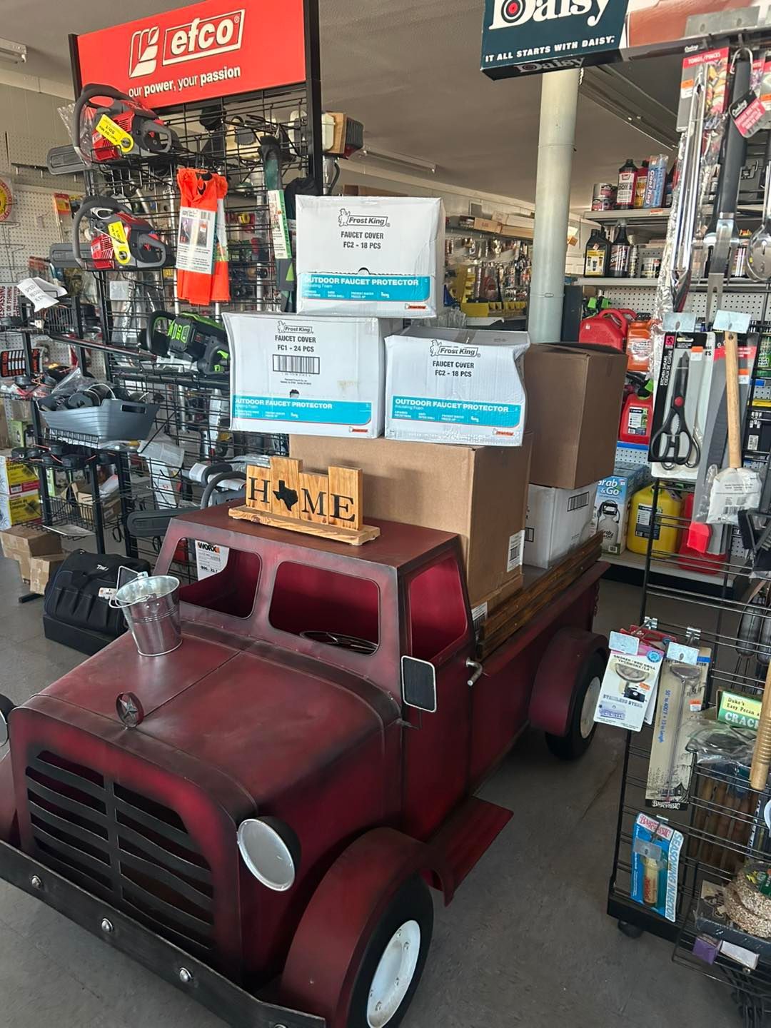 A red truck is sitting on top of a stack of boxes in a store.