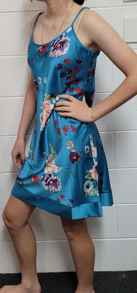 Woman in Teal Floral Dress Poses With Hand on Hip — Shona's Lingerie in Hermit Park, QLD